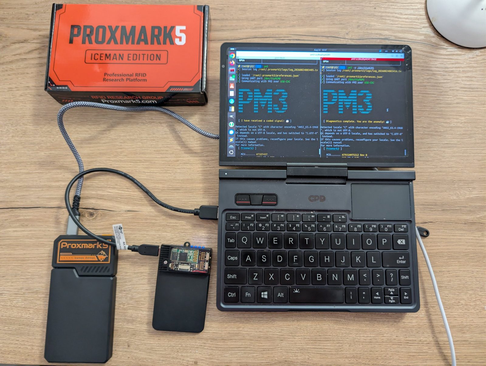 A pocket laptop running RF Swift with two terminals side by side, one driving a Proxmark5 and one a Proxmark3, both plugged in over USB, next to the Proxmark5 Iceman Edition box.